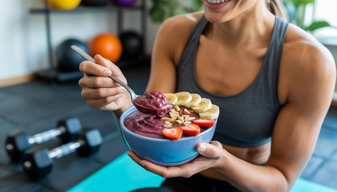 A person in a modern home gym smiling while holding an acai protein bowl, with dumbbells and a yoga mat in the background, showcasing a healthy lifestyle.