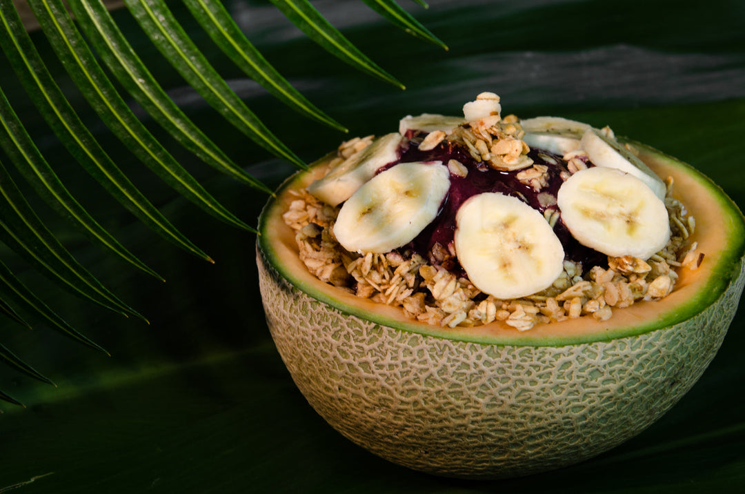 A vibrant arrangement of acai and dragon fruit products, including packets, pouches, bowls, and coconuts, set in a health-focused, warm-toned display.