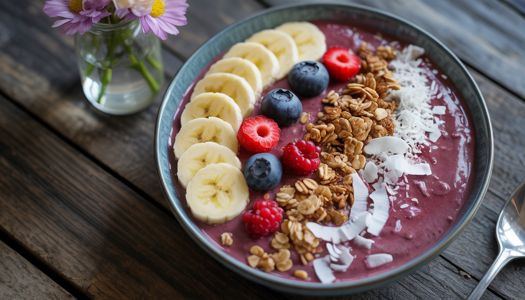 A colorful acai breakfast bowl with banana, berries, granola, coconut flakes, and honey on a wooden table.